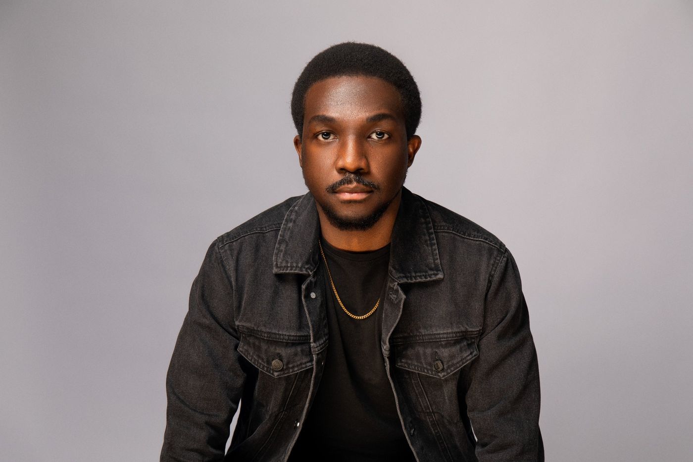 Press photo: headshot in a black denim jacket